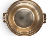 a metal bowl with a handle on a white surface