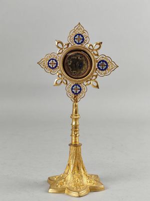 une croix en or sur laquelle figure une horloge bleue et blanche