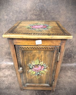 a small wooden cabinet with flowers painted on it