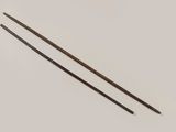 two wooden knitting needles on a white surface