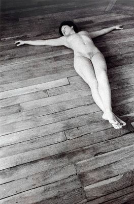 black and white photograph of a naked woman laying on a wooden floor