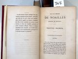 un livre ouvert posé sur une table, à côté d'une pile de livres