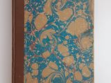 un livre marron et bleu posé sur une table blanche