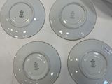 four white plates with designs on them sitting on a table