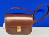 un sac à main en cuir marron orné d'une boucle dorée sur fond bleu