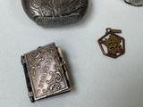 a small silver box with a book on it next to other silver objects