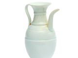 un vase blanc muni d'une anse, posé sur une table