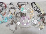 many different types of necklaces and bracelets on the table