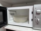 a microwave with a bowl inside of it on a shelf