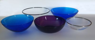 four different colored bowls sitting on top of a white table