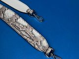 a snake skin strap with a metal clasp on a blue surface