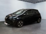 La voiture noire est garée dans une grande pièce aux murs blancs.
