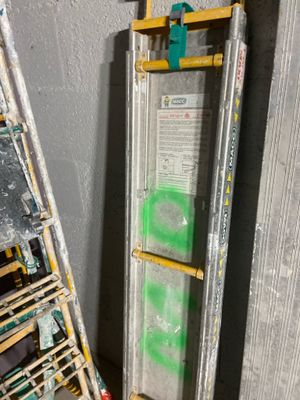a ladder leaning against a wall next to a ladder with a sign on it