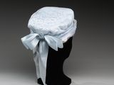 un chapeau blanc orné d'un ruban bleu et d'un nœud, posé sur la tête d'un mannequin