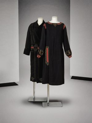deux robes noires et rouges posées sur un portant dans une pièce