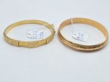 two gold bang bracelets with a tag on them