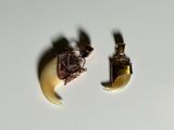 two pieces of jewelry sitting on a white surface