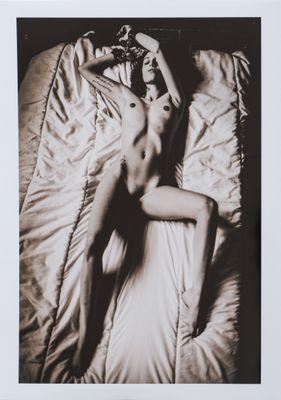 black and white photograph of a naked woman laying on a bed