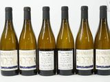 six bouteilles de vin sont alignées sur une surface blanche