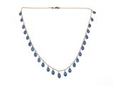 un collier en or orné de gouttes de verre bleues suspendues à une chaîne