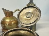 a small metal container with a lid on a table next to a vase