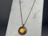 une pièce d'or suspendue à une chaîne en or, posée sur un socle en marbre