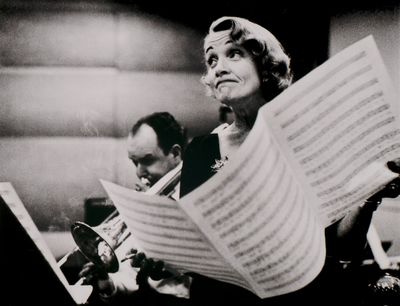 black and white photograph of a woman holding a sheet of music