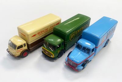 trois camions miniatures posés les uns à côté des autres sur une surface blanche