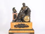une statue représentant un homme assis sur une horloge surmontée d'un oiseau