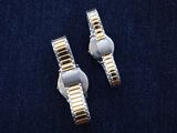 two silver and gold wrist watches on a blue surface