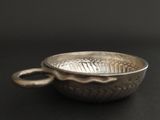 a silver bowl with a handle on a black surface