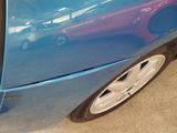 a close up of a blue car with purple paint on it