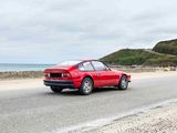 a red car driving down the road by the ocean