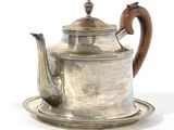 a silver tea pot with a wooden handle on a silver plate