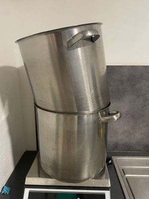 une grande casserole en métal posée sur une balance dans une cuisine