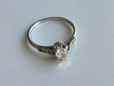 une bague sertie d'un diamant, posée sur une surface blanche