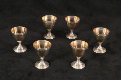six gobelets en argent posés sur une surface noire