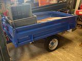 une remorque bleue surmontée d'une caisse, dans un garage