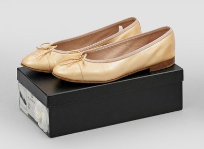 une paire de chaussons de danse en or pour femme, présentée dans une boîte noire
