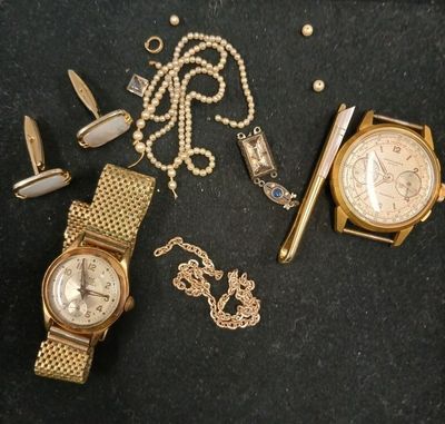 une montre en or, une chaîne en or et une montre en or posées sur un fond noir