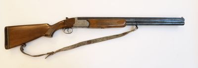 un gros plan d'un fusil posé sur une surface blanche, muni d'une sangle