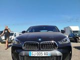 a man standing next to a bmw car in a parking lot
