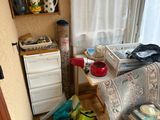 une chambre encombrée avec un lit, une commode et une fenêtre