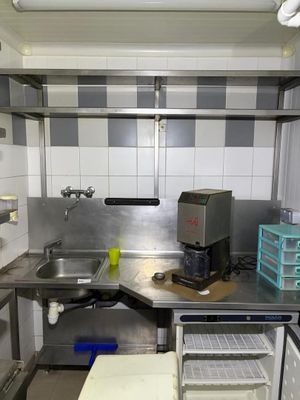 une petite cuisine avec des plans de travail en inox et un évier