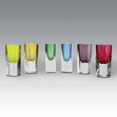 four different colored shot glasses are lined up in a row
