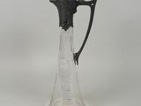a glass pitcher with a black handle on a white table