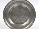 a silver plate with a design on it on a stand