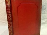 an old red book sitting on top of a white table