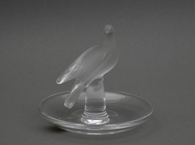 un oiseau en verre posé sur une assiette en verre