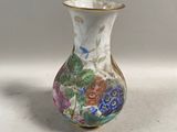 un petit vase décoré de fleurs, posé sur une table
